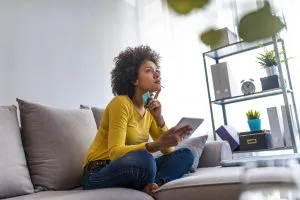  Mulher que compra on-line com o laptop em casa na sala de estar. Mulher de compras on-line. Mulher feliz, compras on-line com cartão de crédito e computador tablet.