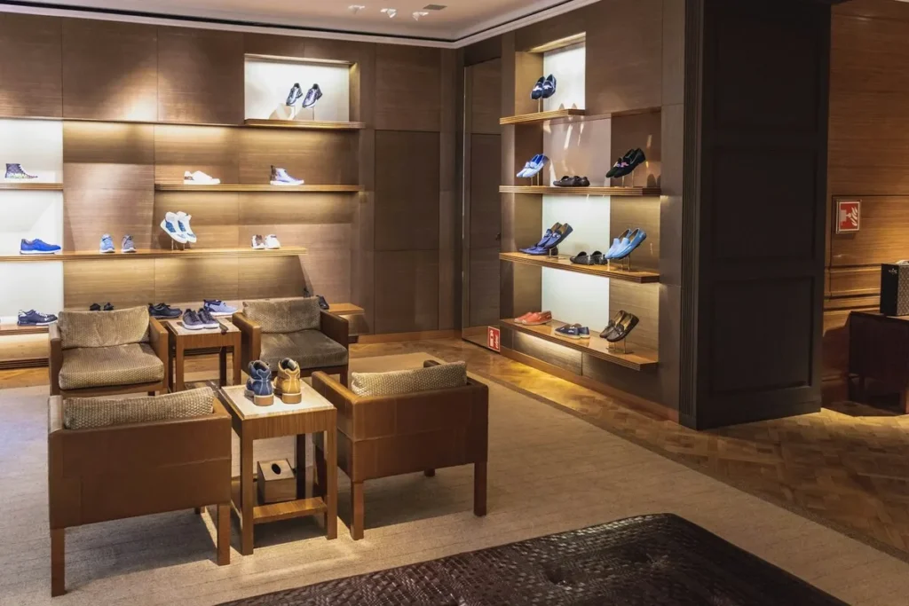 Loja de luxo com sapatos exibidos em prateleiras iluminadas e áreas de estar, otimizando o ticket médio.
