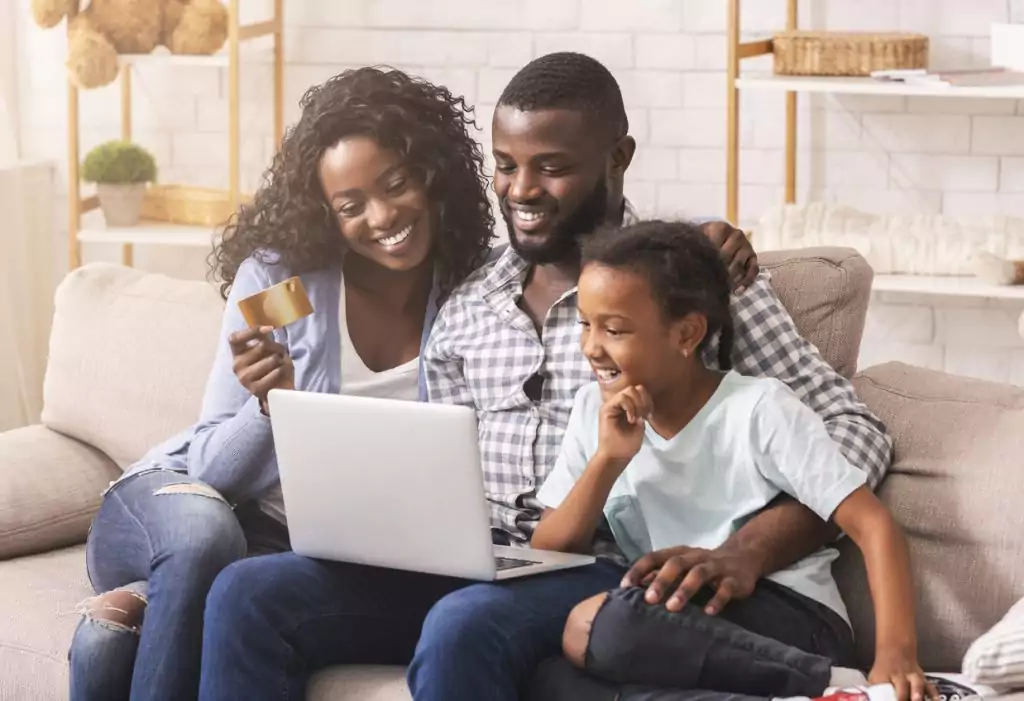 Família afro-americana fazendo compras online com laptop e cartão de crédito que são os novos clientes pós pandemia.