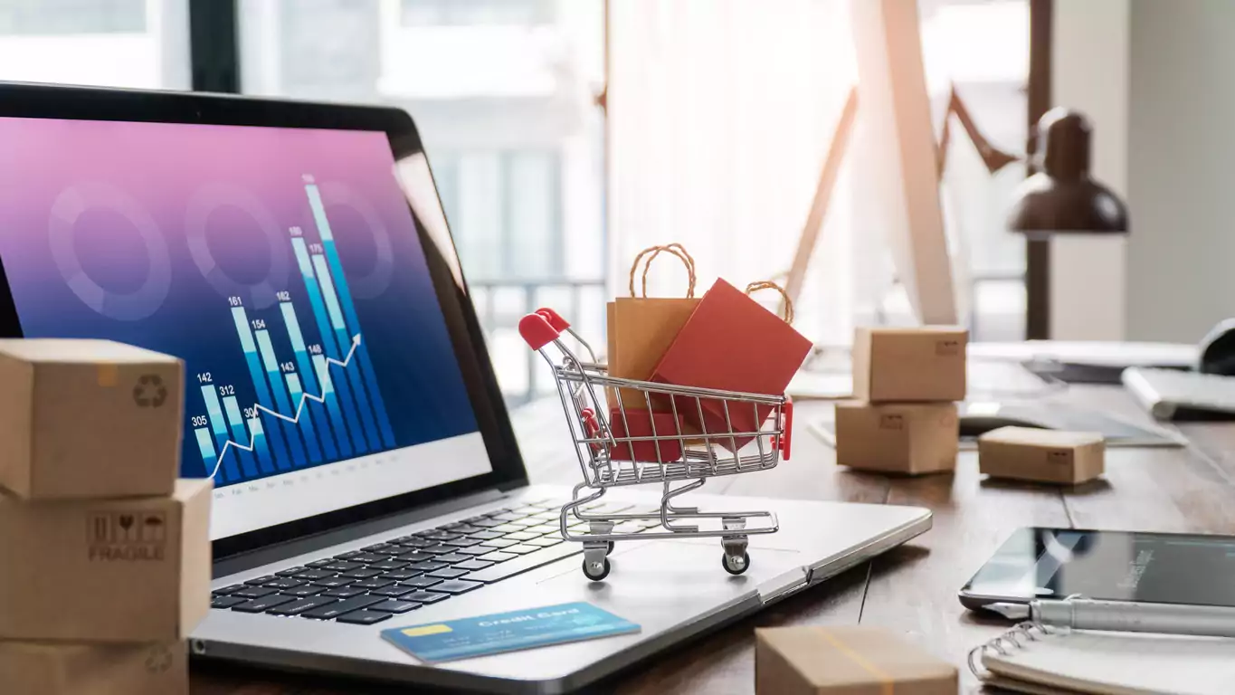 Sacolas de compras no carrinho de compras e cartão de crédito no laptop com caixas de papel na tabela e gráfico de crescimento econômico de dados de vendas na tela, compra e venda de serviços on-line na rede, compras on-line e conceito de comércio eletrônico.