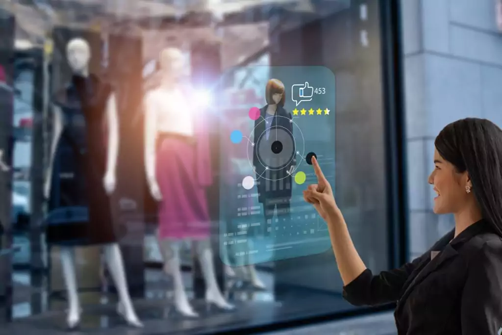 Uma mulher de cabelo preto e blusa preta está parada em frente a uma vitrine de roupas enquanto interage com um holograma de uma peça de roupa criado por meio de inteligencia artificial