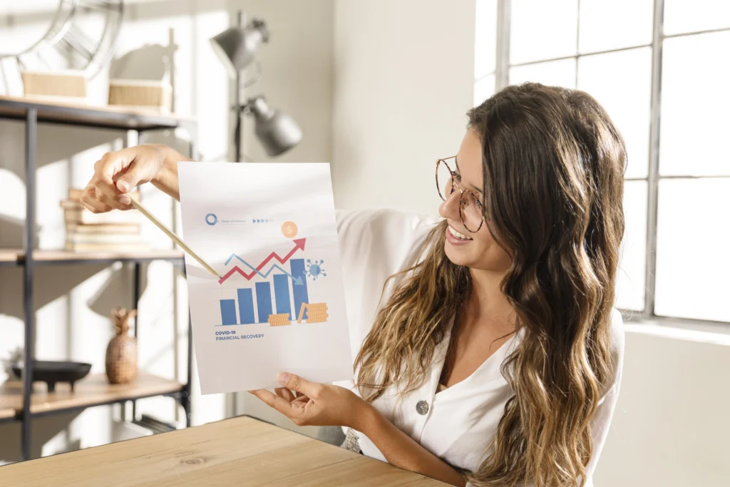 pessoa segurando um papel com gráficos de crescimento de vendas e apontando para as setas crescentes