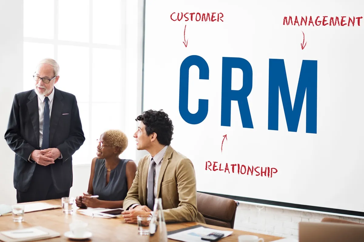 Apresentação sobre CRM em reunião de negócios, com executivos discutindo estratégias para gestão de relacionamento com clientes.