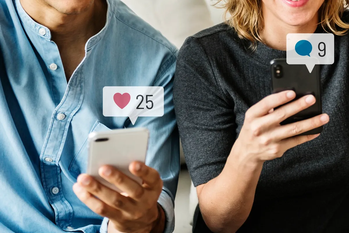 Homem e mulher sentados lado a lado segurando smartphones, com ícones flutuantes de engajamento: coração com ‘25’ e balão de comentário com ‘9’.