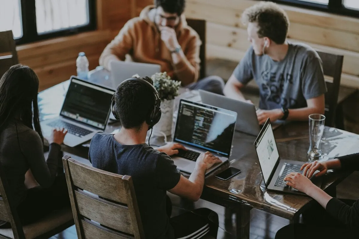 Equipe de desenvolvedores trabalhando com notebooks em ambiente colaborativo.