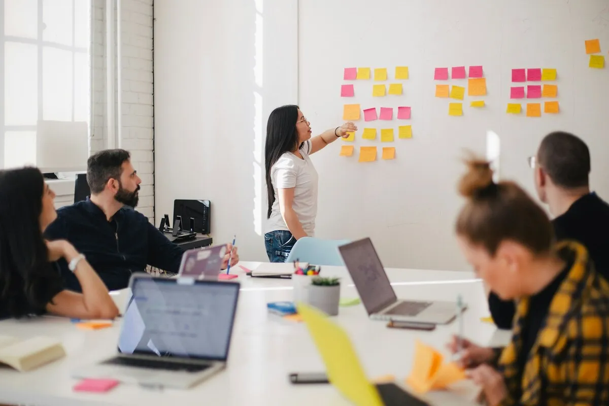 Equipe em reunião colaborativa com post-its em um quadro branco