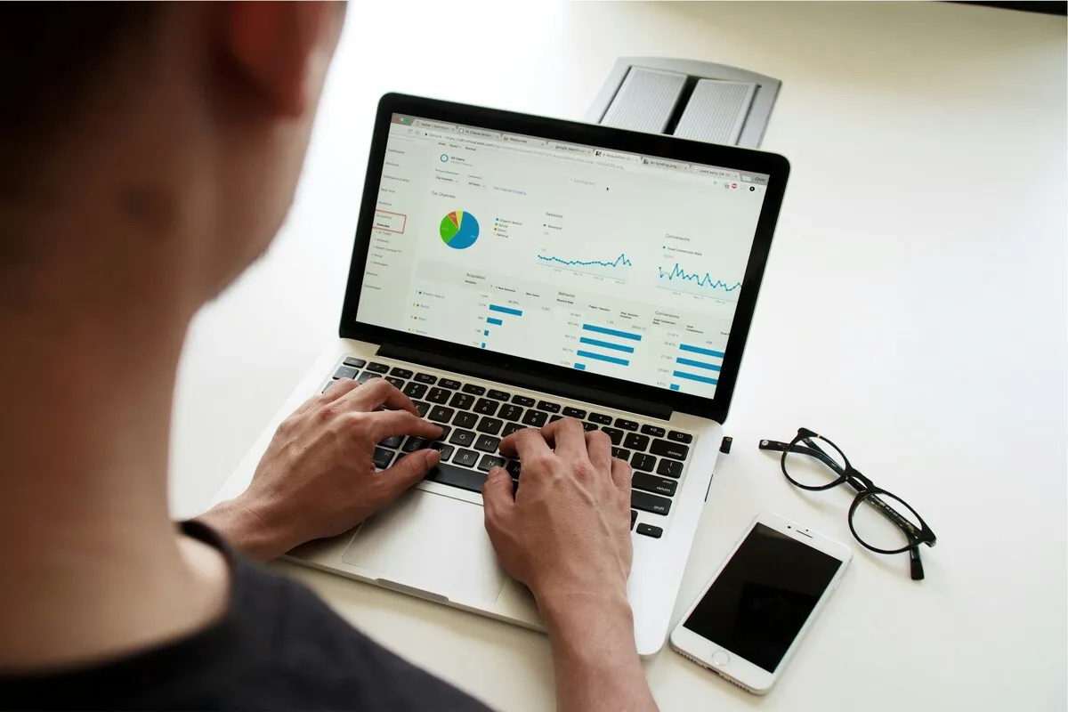 Pessoa analisando gráficos e métricas em um notebook com painel de dados