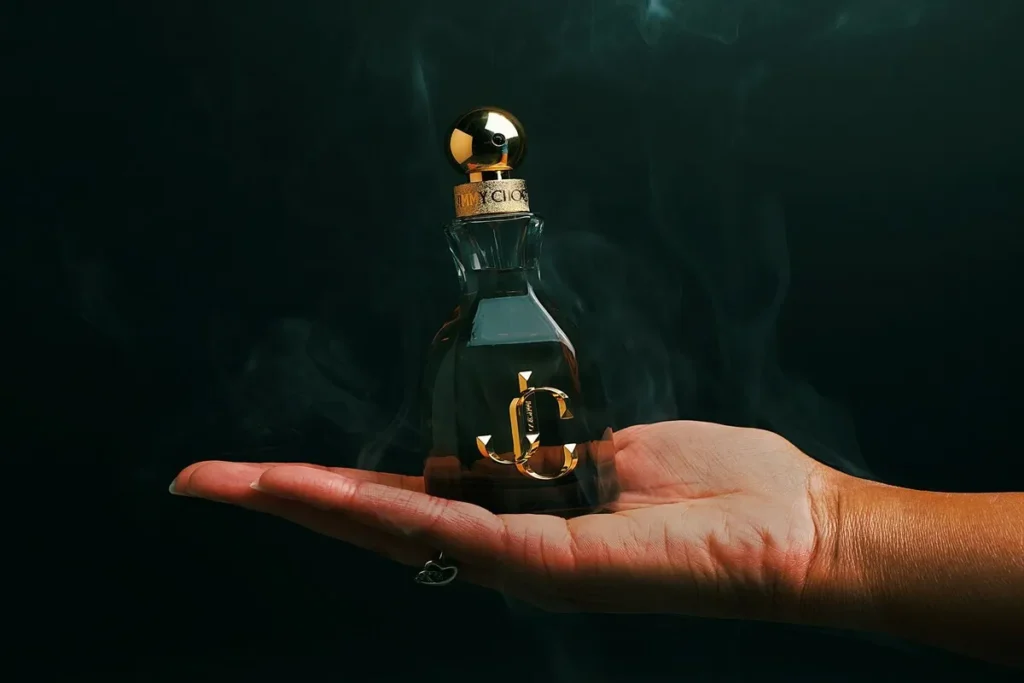 Frasco de perfume luxuoso na palma da mão com fundo escuro e vapor perfumado, simbolizando o sentido do olfato.