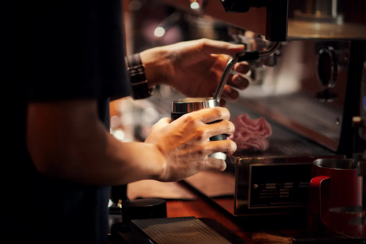 Barista preparando café com máquina profissional de espresso em cafeteria.