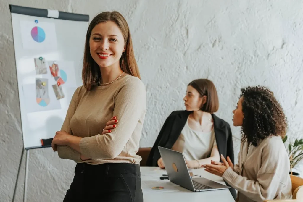 Mulher sorridente em foco com equipe feminina em reunião de negócios ao fundo