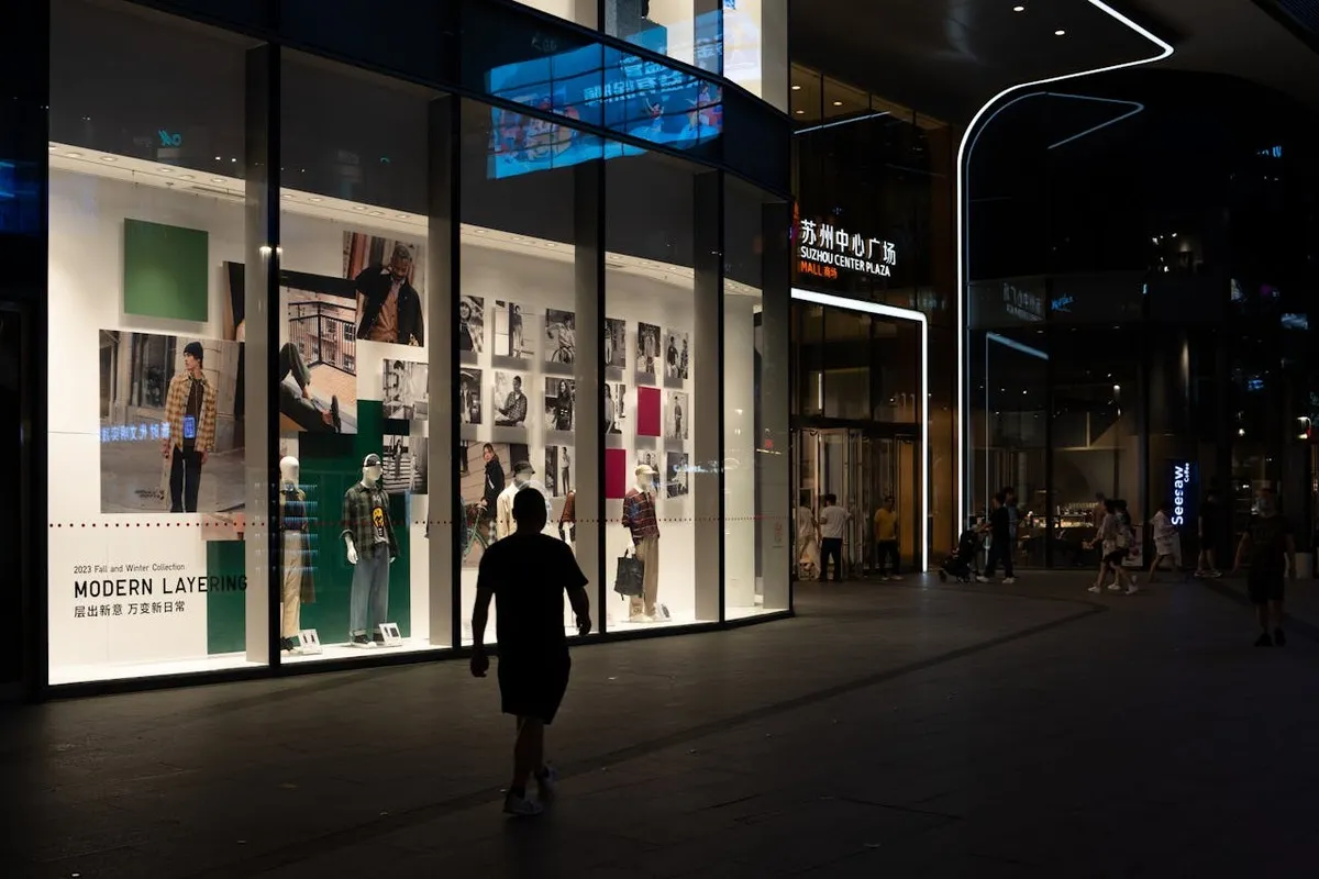 Fachada noturna de uma loja moderna com um layout de loja convidativo, exibindo manequins e displays de moda.