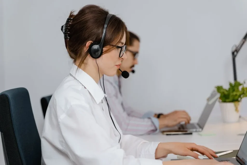 Mulher usando fone de ouvido e digitando em um laptop, representando um profissional de atendimento ao cliente focado em CX em um call center moderno.