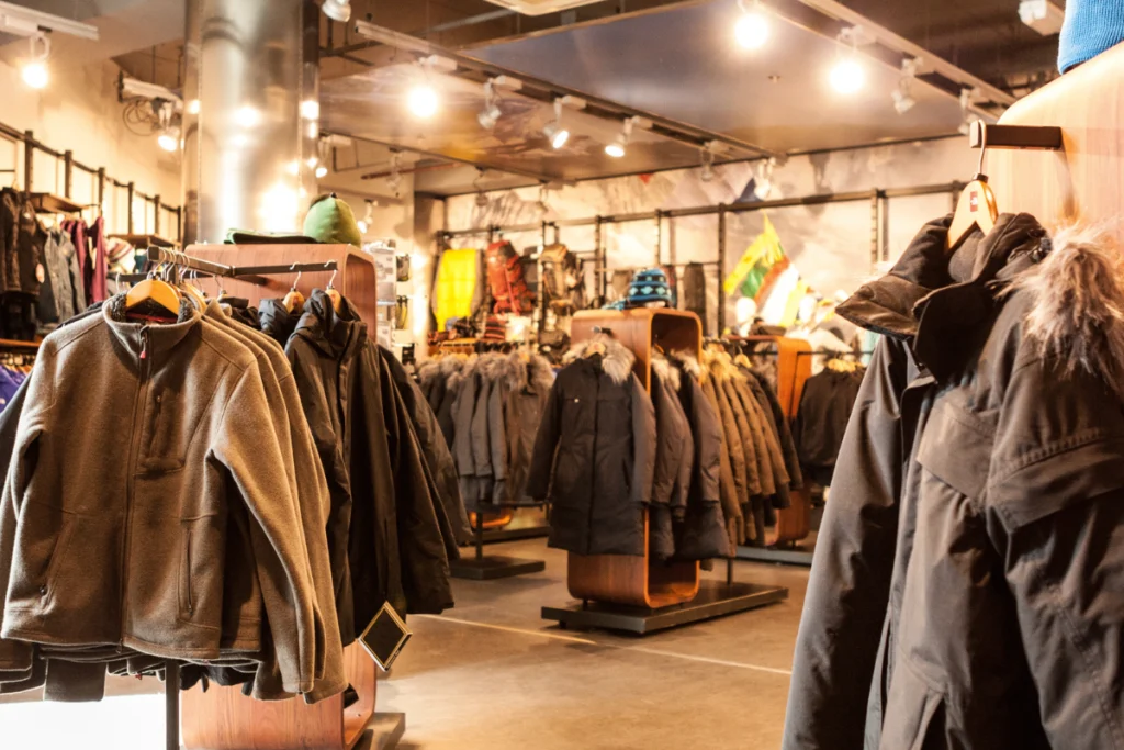Interior de loja especializada em roupas de frio com diversos casacos de inverno pendurados em araras de madeira.