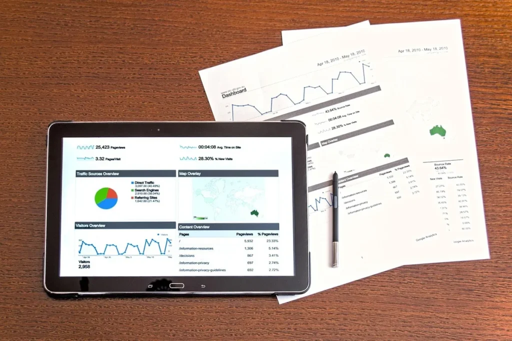  Tablet exibindo gráficos de análise de tráfego e relatórios impressos com dados de desempenho, ilustrando a importância de benchmarks para a tomada de decisões.