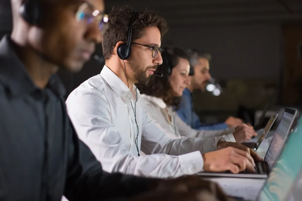 Equipe de atendentes em call center usando headsets e laptops, focados em alcançar alta FCR (Resolução no Primeiro Contato).