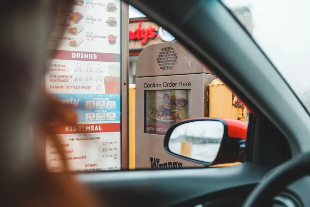 Visão de dentro de um carro no drive-thru de fast-food, mostrando a conveniência de um serviço franqueado.