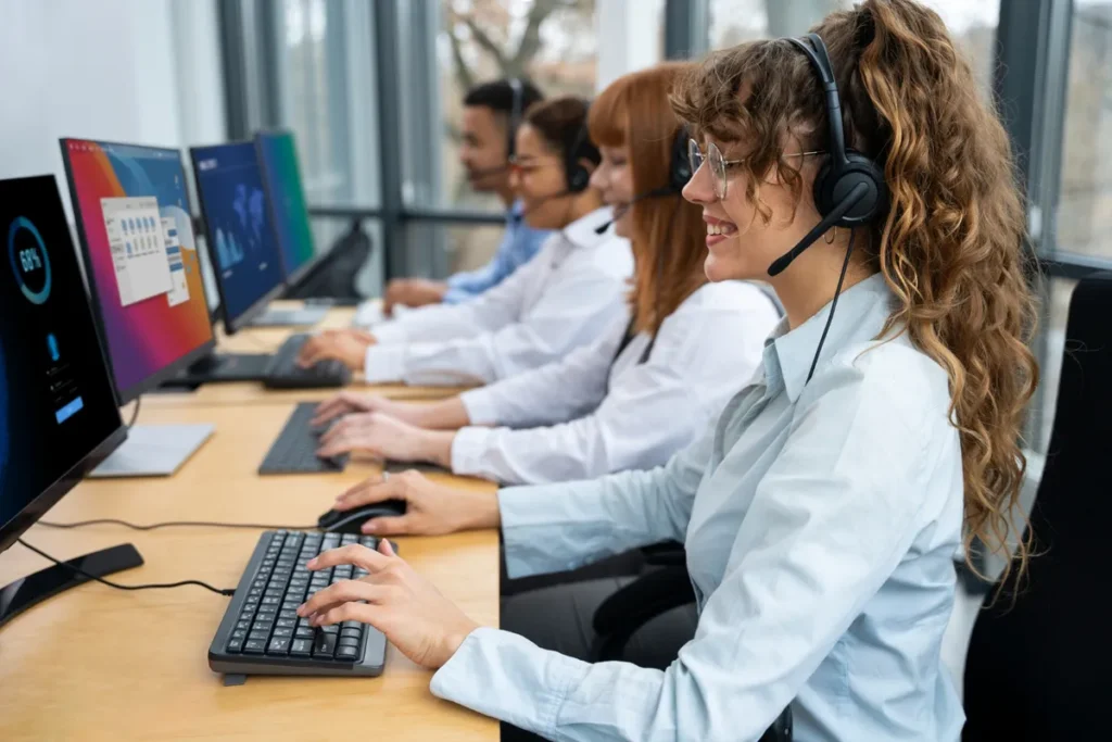 Equipe de funcionários de telemarketing trabalhando lado a lado com headsets, mostrando a coesão e o trabalho em equipe em um escritório.