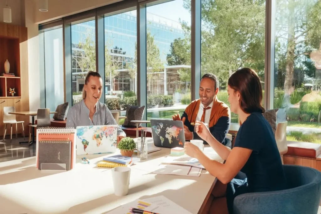 Equipe diversificada fazendo planejamento estratégico em uma sala de reuniões com grandes janelas e vista para a natureza.