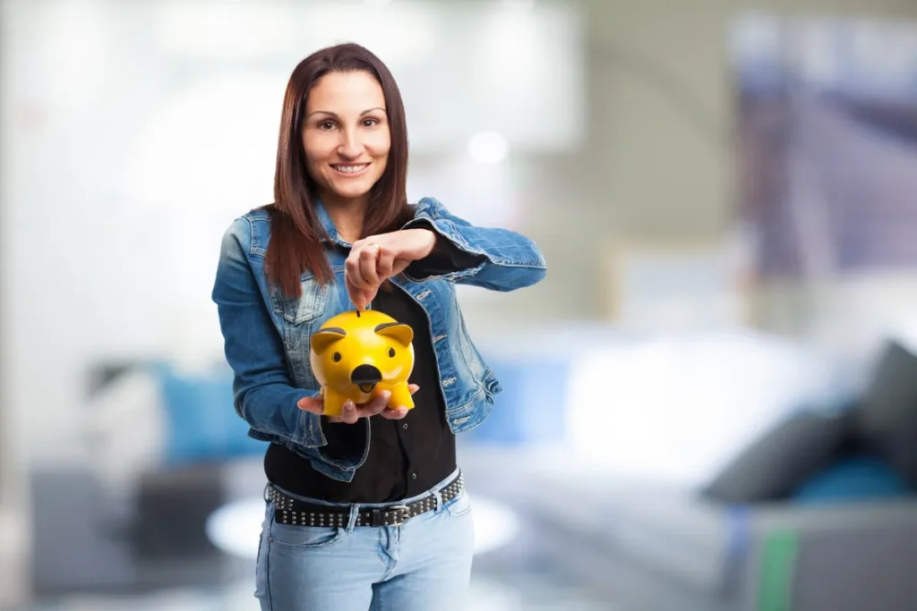 Uma mulher sorrindo, com um cofrinho de porco amarelo, simbolizando o ato de economizar e o uso da renda extra para alcançar objetivos financeiros.