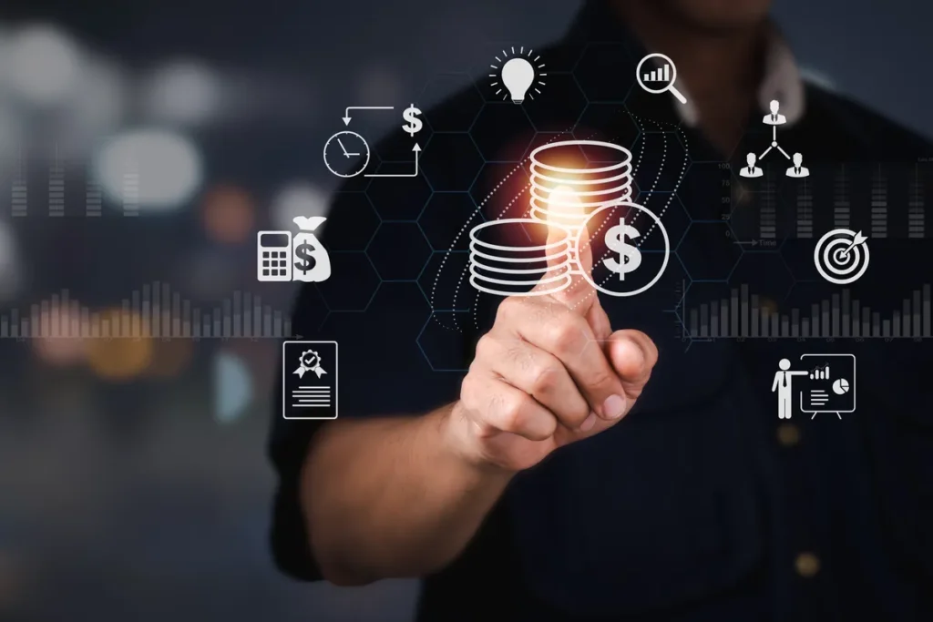 Uma mão aponta para um ícone digital de moedas, rodeado por outros ícones de negócios, como lupa, alvo, gráfico e calculadora. A imagem simboliza as estratégias e o planejamento para analisar e aumentar a revenue de um negócio.