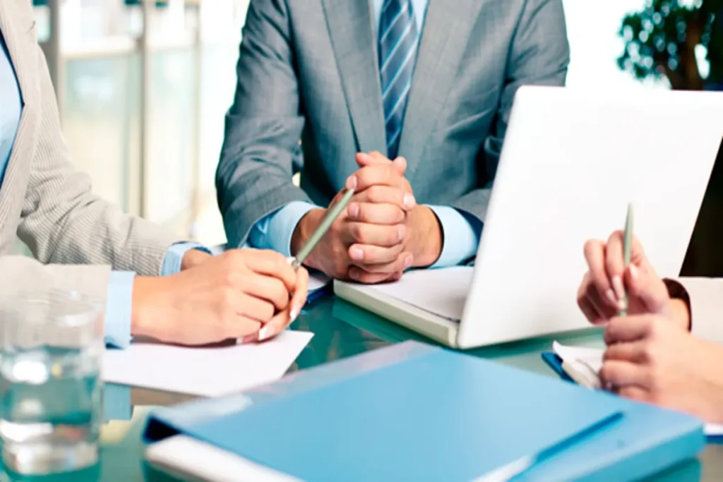 Uma equipe de negócios em uma reunião no escritório, discutindo e definindo metas de trabalho. A imagem representa o planejamento estratégico e a colaboração profissional.