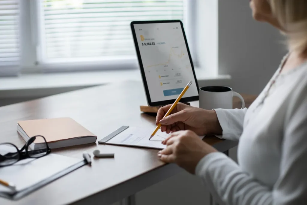 Um homem sentado em uma mesa, em um escritório, olhando atentamente para um monitor de computador que mostra um mapa com um ícone de pino de localização, representando o rastreio de pedidos.