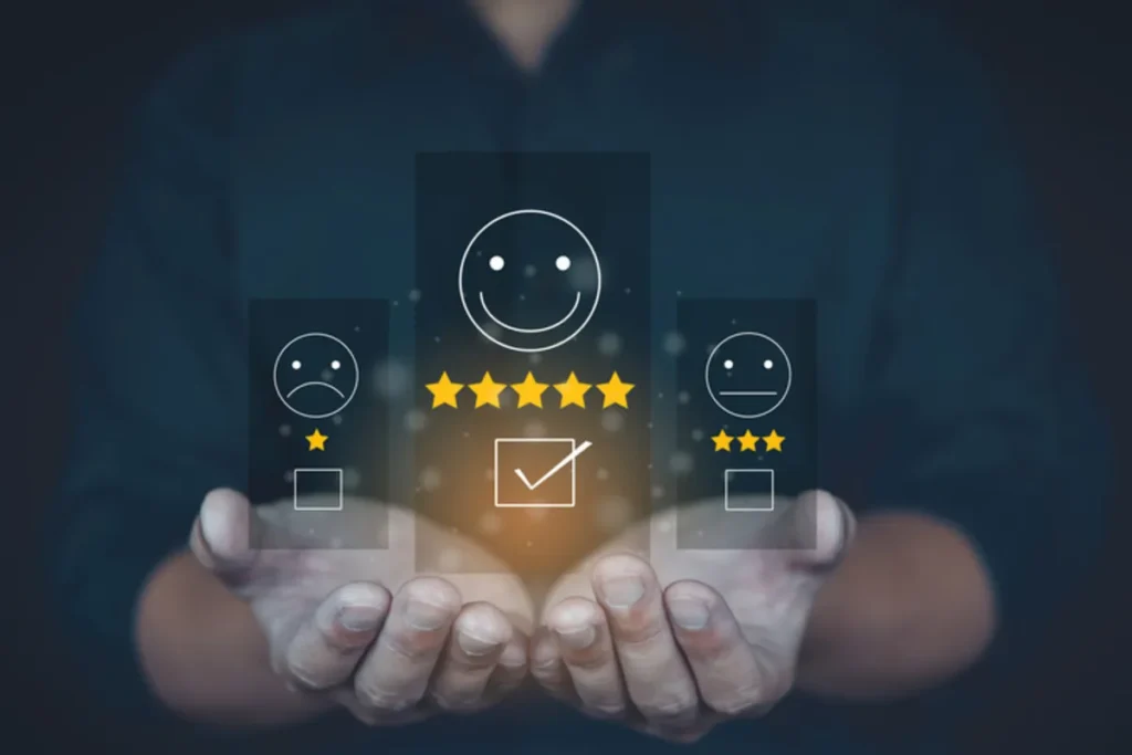 Mãos segurando um display digital que mostra opções de avaliação de satisfação, com um ícone de rosto sorridente e 5 estrelas destacado. A imagem representa a coleta de feedback e medição de satisfação do cliente.